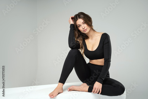 Fashionable young fit Woman in black sporty clothes posing Over Studio Background