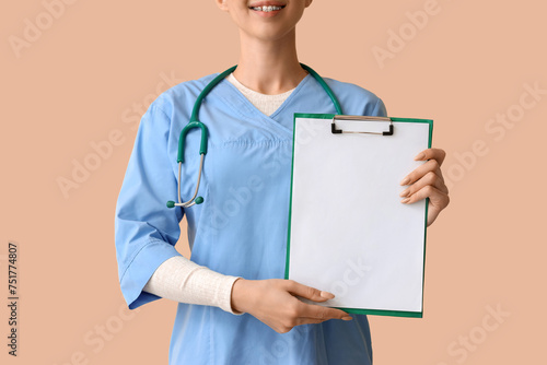Female medical intern with clipboard on beige background