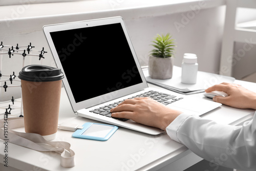 Female doctor working with laptop at table in clinic  closeup