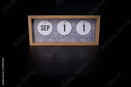 A wooden calendar block showing the date September 11th on a dark black background, save the date or date of event concept