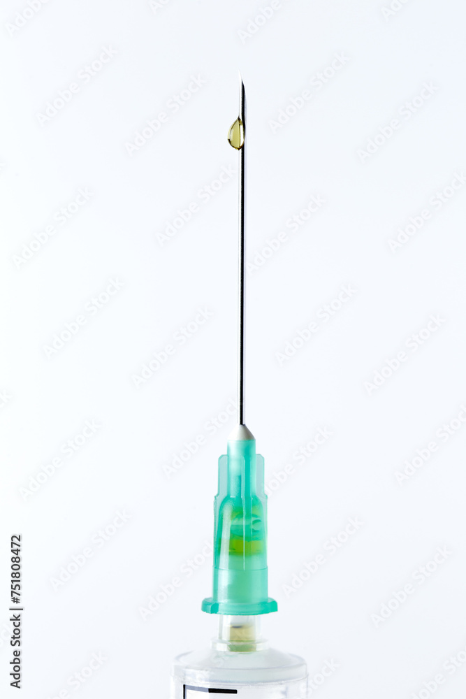 Close-up of the needle of a syringe, with a drop on the needle, vertical. White background. Vertical. Close-up of the needle of a syringe, with a drop on the needle, vertical. White background. Vertical.