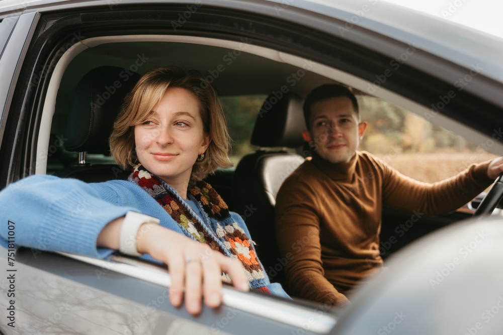Adult couple on a autumn road trip, man and woman sitting in the car and looking through the window