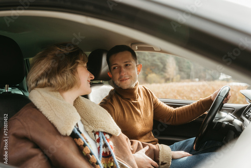 Adult couple on a autumn road trip, man and woman sitting in the car and looking on each other © Romvy