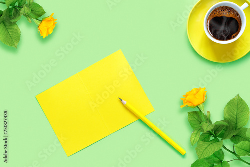 Bouquet of beautiful yellow roses and cup of hot fresh aromatic coffee on  green paper background