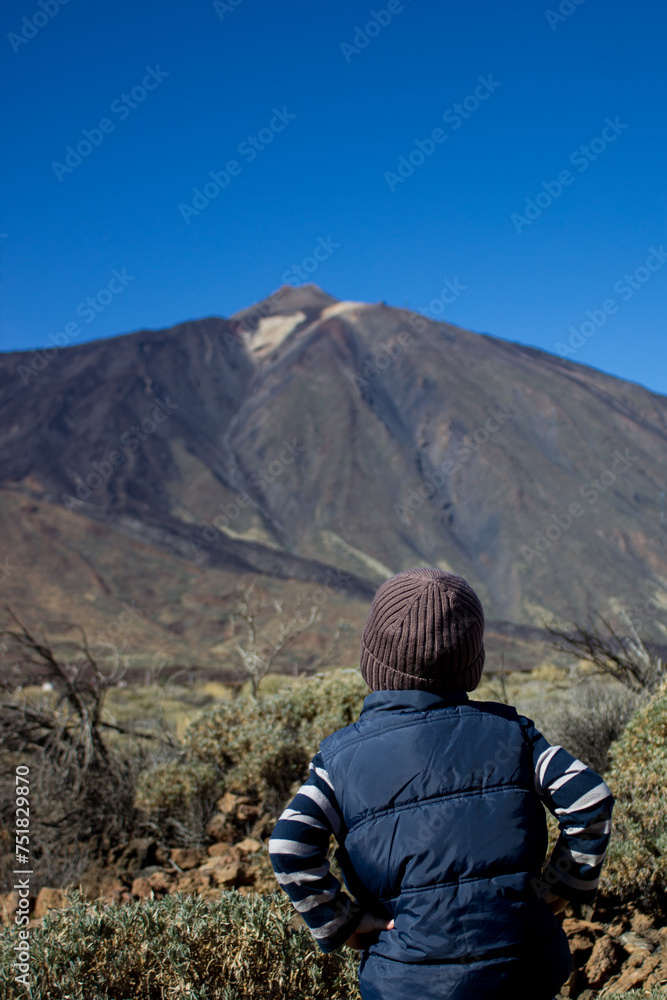 Naklejka premium Young traveler. Boy of 4 years old looks at volcano Teide in front of him.