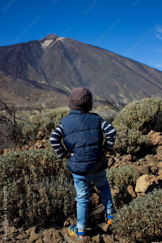 Naklejka premium Young traveler. Boy of 4 years old looks at volcano Teide in front of him.