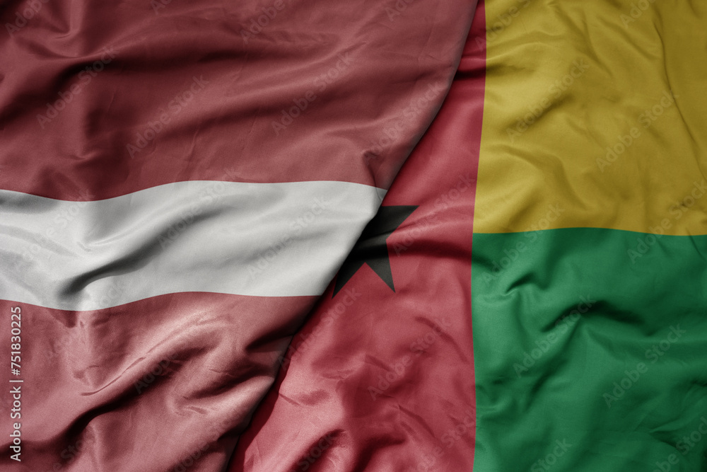 big waving national colorful flag of guinea bissau and national flag of latvia.