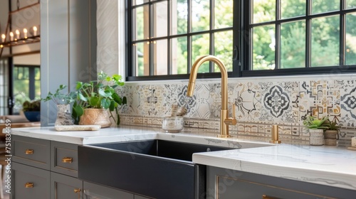 A remodeled modern farmhouse kitchen features a stunning sink adorned with a gold faucet  complemented by a black farmhouse sink  white granite countertops  and a tiled backsplash