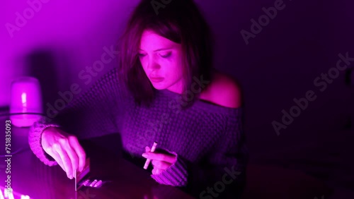 addicted woman in a den in a neon light sweater snorts drugs from the table. drug addiction photo