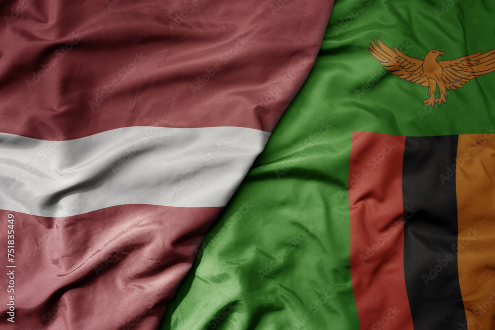 big waving national colorful flag of zambia and national flag of latvia.