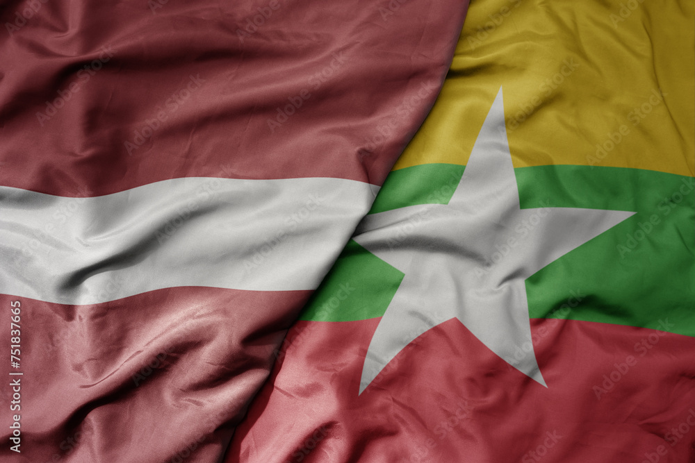 big waving national colorful flag of myanmar and national flag of latvia.