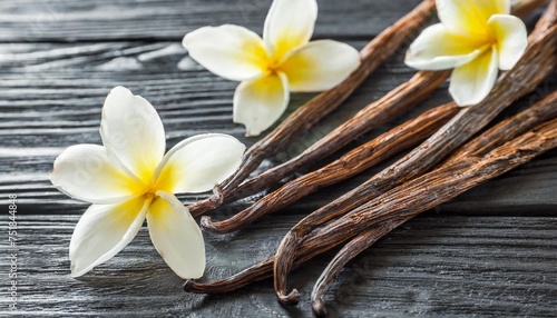 board with aromatic vanilla sticks and flowers on black wooden background