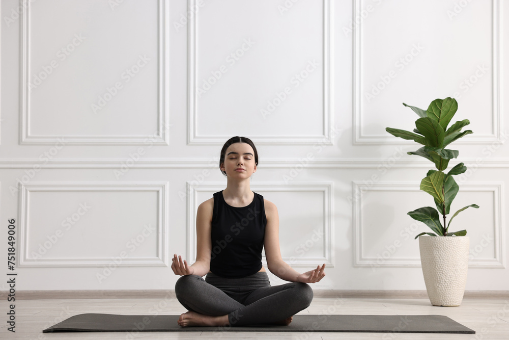 Beautiful girl meditating on mat in yoga studio Beautiful girl meditating on mat in yoga studio