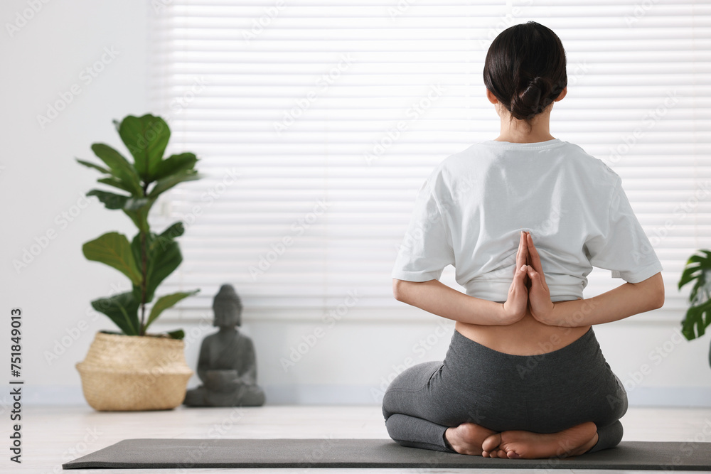 Girl practicing vajrasana with namaste behind back on mat in yoga studio Girl practicing vajrasana with namaste behind back on mat in yoga studio