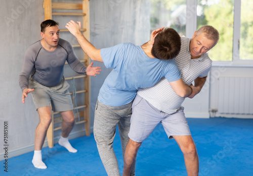 Elderly man and young man training self-defense techniques in studio.. © JackF