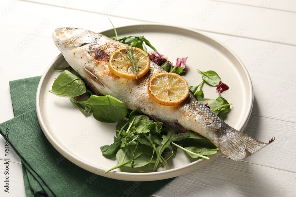Baked fish with spinach and lemon on white wooden table, closeup Baked fish with spinach and lemon on white wooden table, closeup