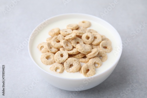 Breakfast cereal. Tasty corn rings with milk in bowl on grey table, closeup