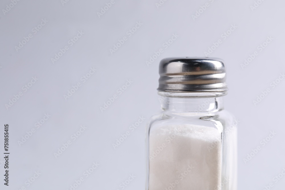 Natural salt in shaker on light grey background, closeup. Space for text Natural salt in shaker on light grey background, closeup. Space for text