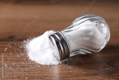 Natural salt and shaker on wooden table, closeup