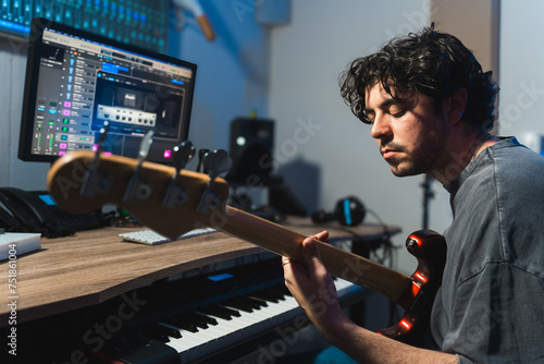 Male musician tuning bass guitar in a modern recording studio photo