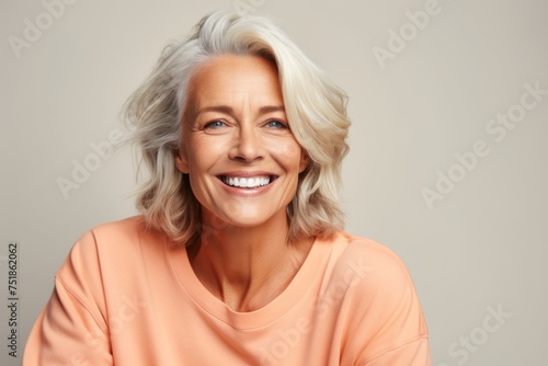 Happy senior woman. Portrait of beautiful mature woman looking at camera and smiling while standing against grey background