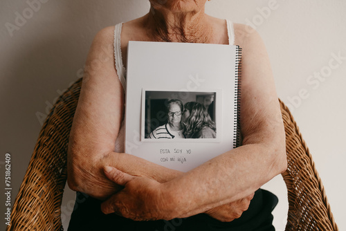 Elderly arms embracing a photo album with cherished memory photo