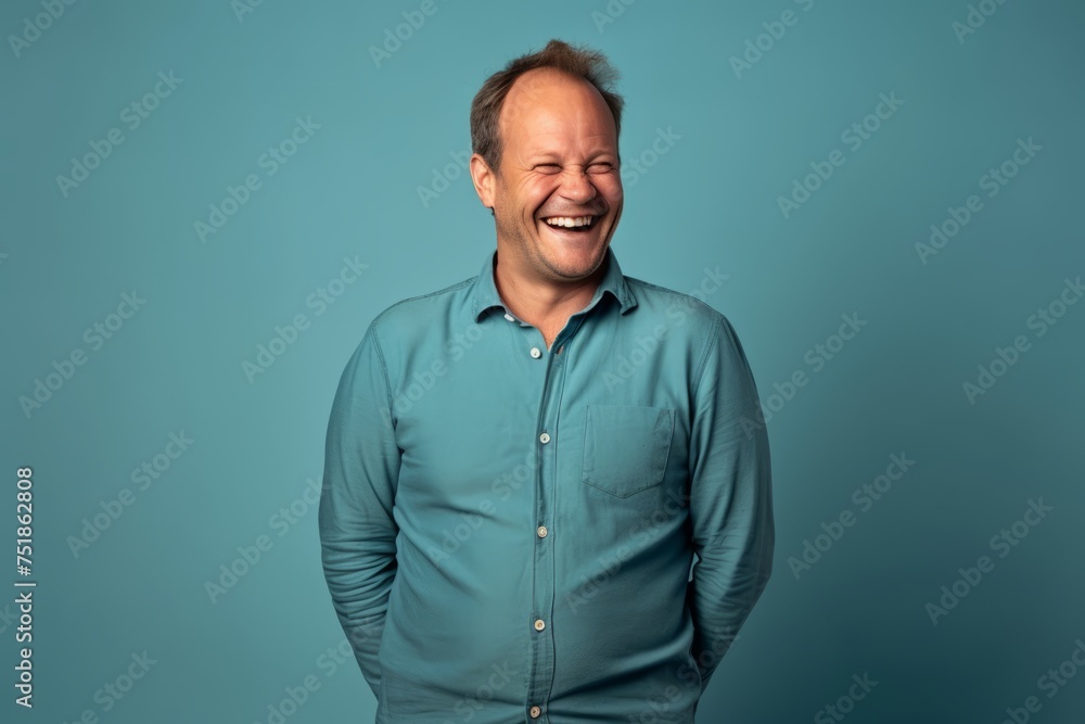 Handsome middle aged man laughing and looking at camera on blue background