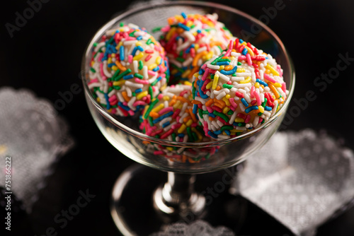 Brigadeiros, beautiful colorful sweets inside a cup on a black reflective surface, selective focus. photo