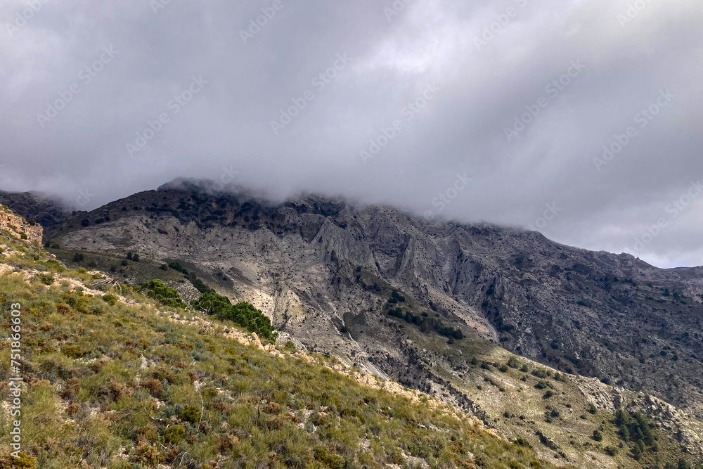 Fog and clouds on hiking trail to Maroma peak in thunderstorm day, Sierra Tejeda, Spain 