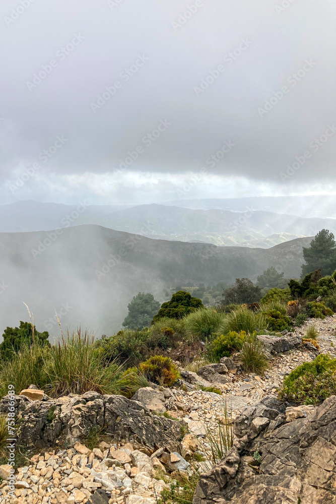Fog and clouds on hiking trail to Maroma peak in thunderstorm day, Sierra Tejeda, Spain 