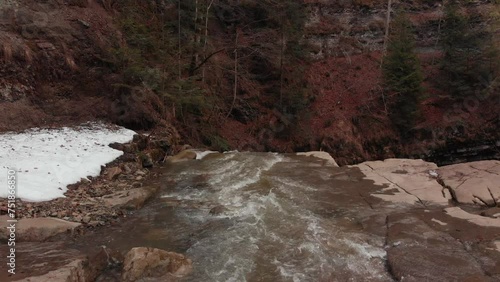 Aerial footage of a river falling into a waterfall from a cliff. 