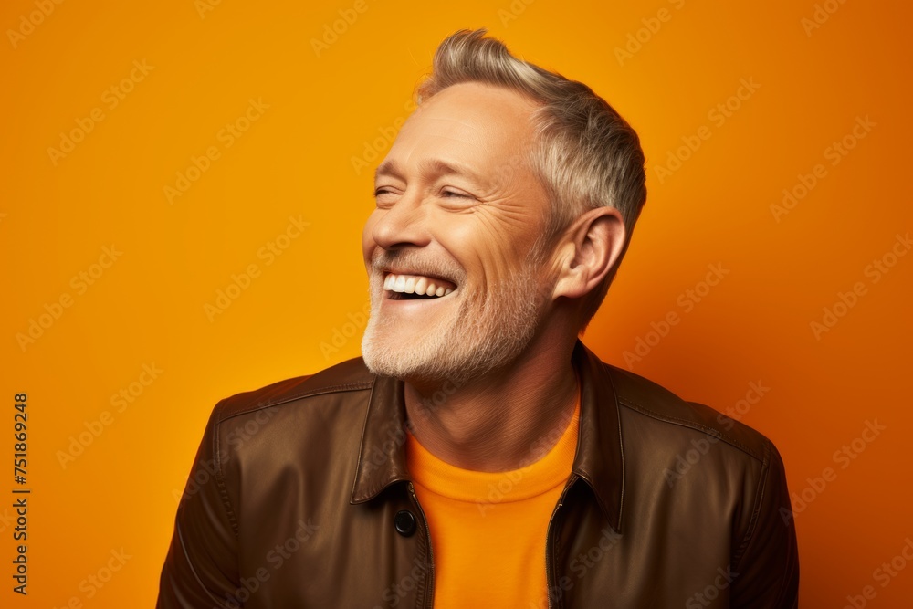 Portrait of a happy senior man in leather jacket over orange background.