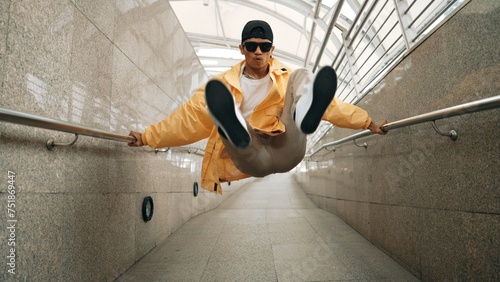 Skilled happy asian hipster walking while dancing in narrow corridor. Close up of break dancer practicing break dance performance. Professional man moving to music. Outdoor sport 2024. Sprightly.