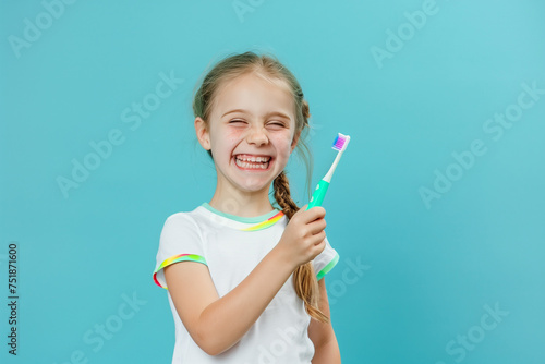 Caucasian girl with toothbrush in her hand, on light blue background