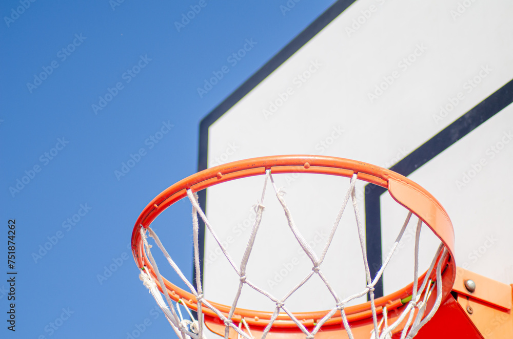 Close up of basketball hoop seen from below on blue sky background