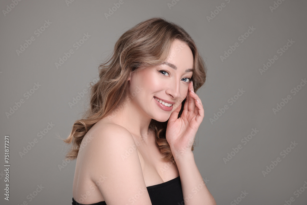 Portrait of smiling woman with curly hair on grey background Portrait of smiling woman with curly hair on grey background