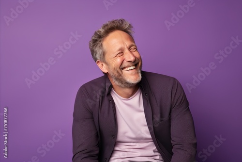 Portrait of a happy senior man laughing while standing against purple background
