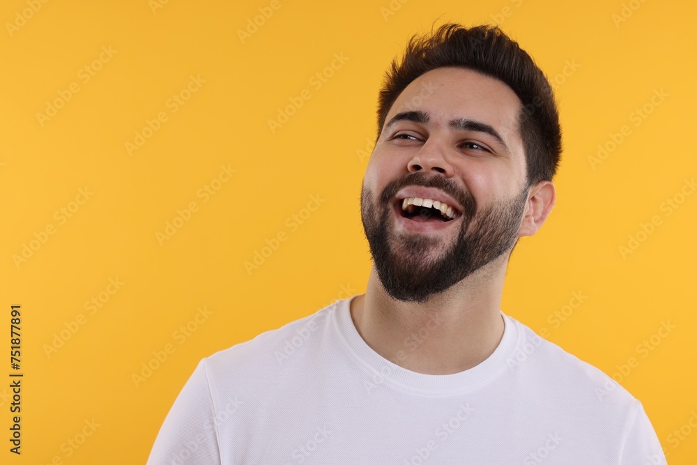 Handsome young man laughing on yellow background, space for text Handsome young man laughing on yellow background, space for text