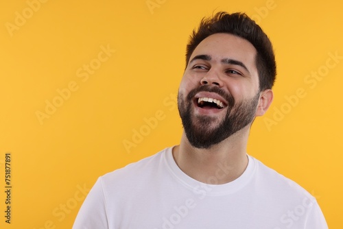 Handsome young man laughing on yellow background, space for text