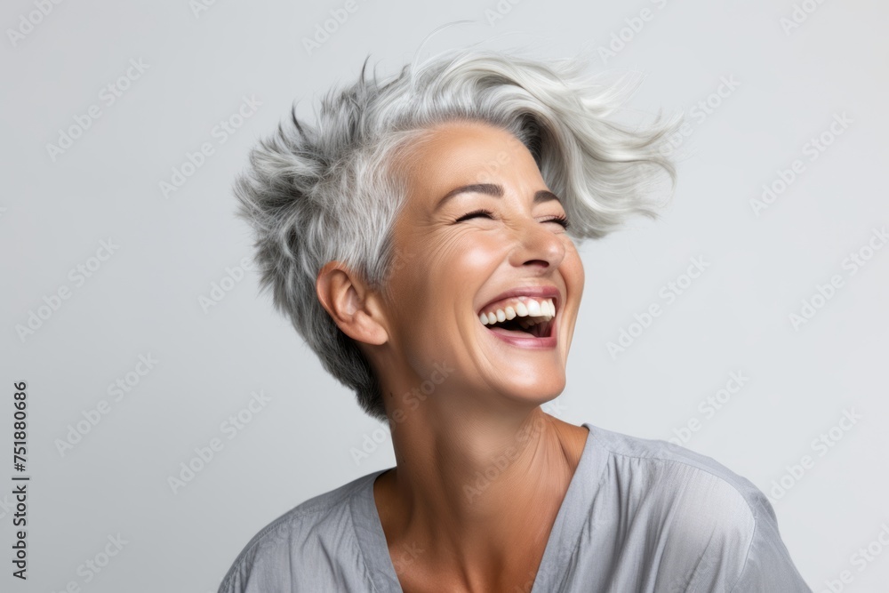 Portrait of a happy senior woman laughing and looking up on grey background Portrait of a happy senior woman laughing and looking up on grey background