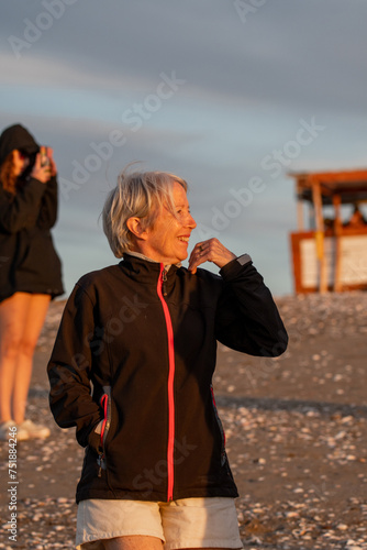 Mujer mayor de 70 años feliz mirando el atardecer, vertical, plano medio photo