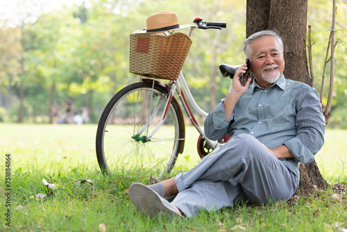 senior man using smartphone and talking to someone in the park