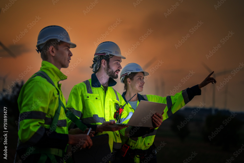 Team Engineers men and woman checking and inspecting on construction with sunset sky. people operation. Wind turbine for electrical of clean energy and environment. Industrial of sustainable. Team Engineers men and woman checking and inspecting on construction with sunset sky. people operation. Wind turbine for electrical of clean energy and environment. Industrial of sustainable.