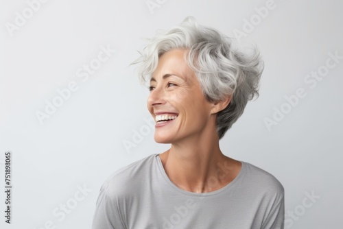Portrait of smiling senior woman with grey hair against white background.