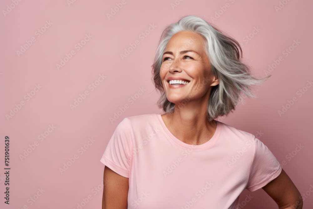 Portrait of a happy senior woman smiling and looking away against pink background Portrait of a happy senior woman smiling and looking away against pink background