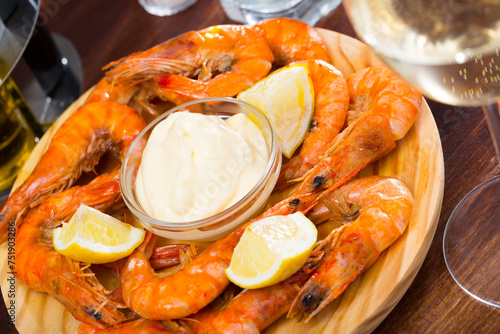 Appetizing baked shrimps with sauce and lemon served on wooden board photo