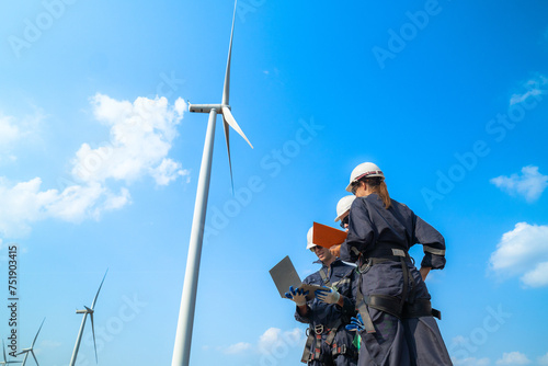 uprisen angle engineers working in fieldwork at outdoor with wind turbine and clear sky. Workers check construction. Wind turbines for electrical clean energy and environment sustainability.