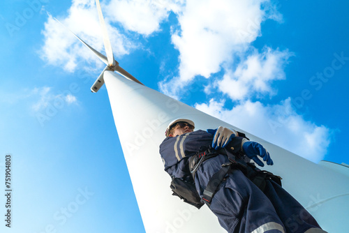 uprisen angle engineer working in fieldwork at outdoor with wind turbine and clear sky. Workers check construction. Wind turbines for electrical clean energy and environment sustainability.