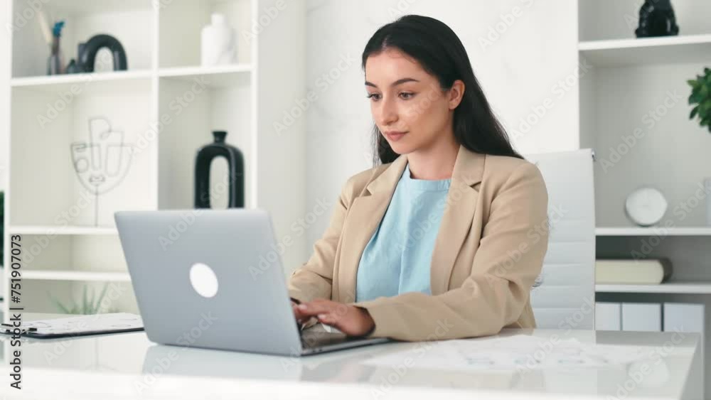 Elegant successful indian or arabian business woman, company employee sitting at workplace in the office, using laptop, working on a project, looks at camera, smiling friendly Elegant successful indian or arabian business woman, company employee sitting at workplace in the office, using laptop, working on a project, looks at camera, smiling friendly