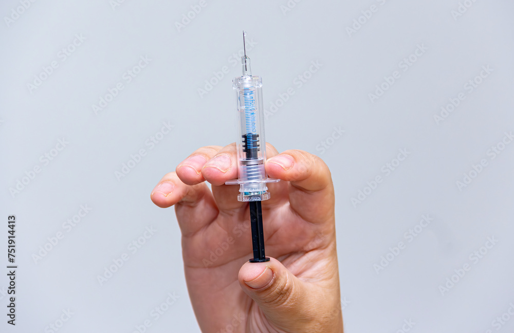 Syringe, medical injection in hand, medicinal plastic vaccination equipment with needle isolated on neutral background Syringe, medical injection in hand, medicinal plastic vaccination equipment with needle isolated on neutral background